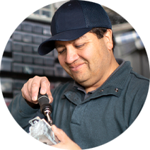 Maintenance man wearing a dark cap and using a screwdriver to fix something