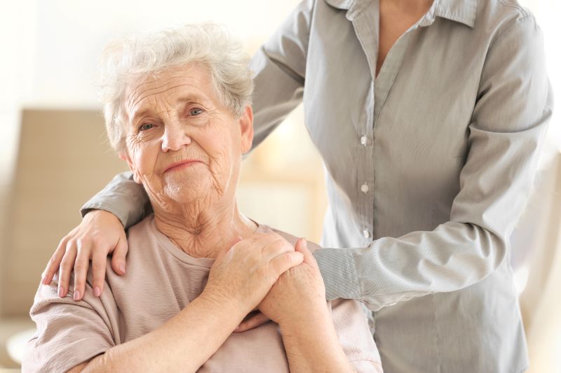 Family member in dress shirt comforting senior woman