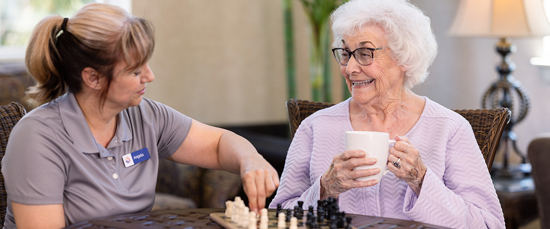 An elderly woman sitting with a caretaker