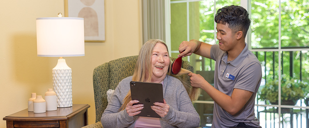 A caretaker brushing a woman's hair